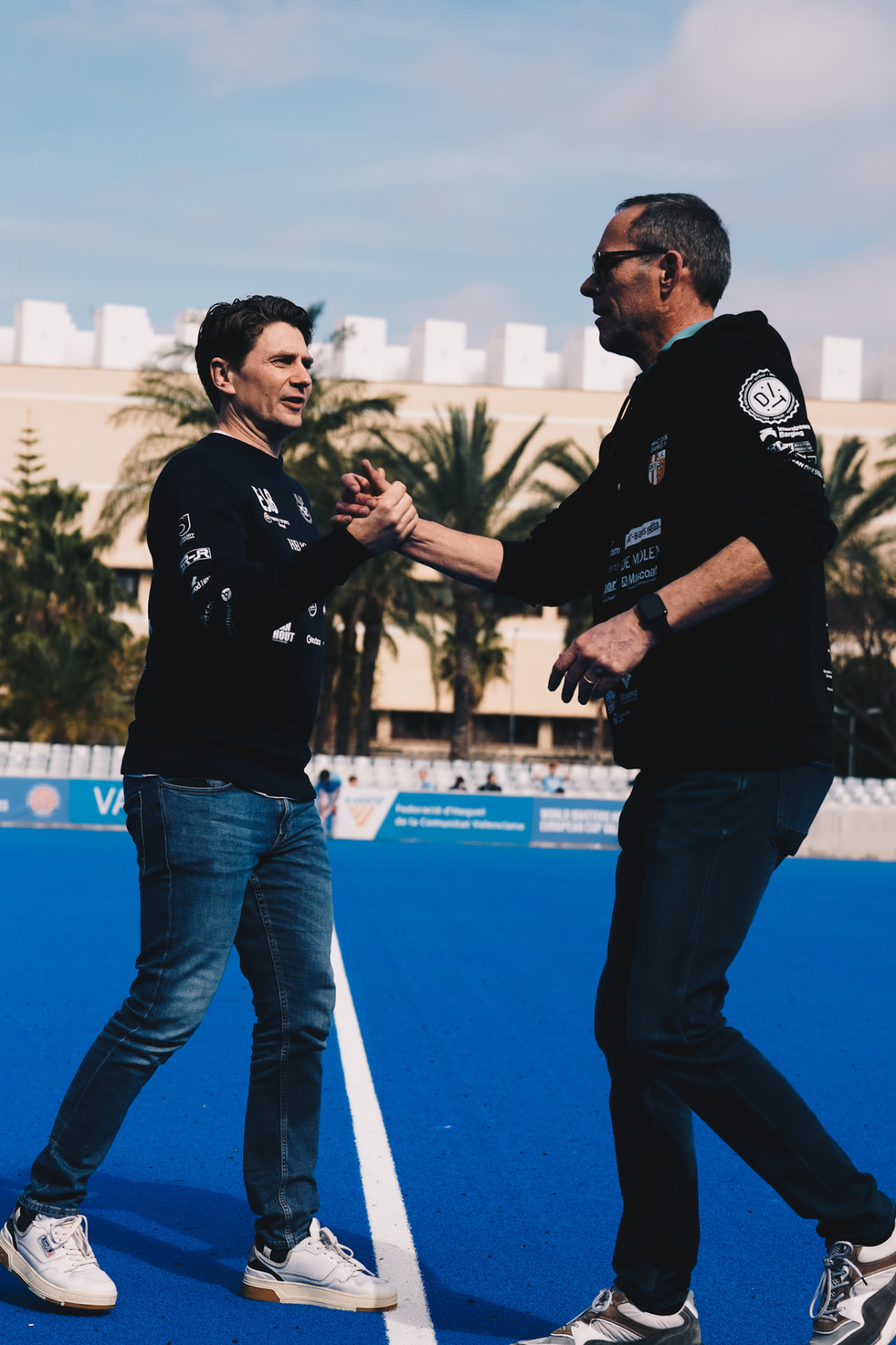 Coaches begroeten elkaar op het blauwe hockeyveld in Valencia