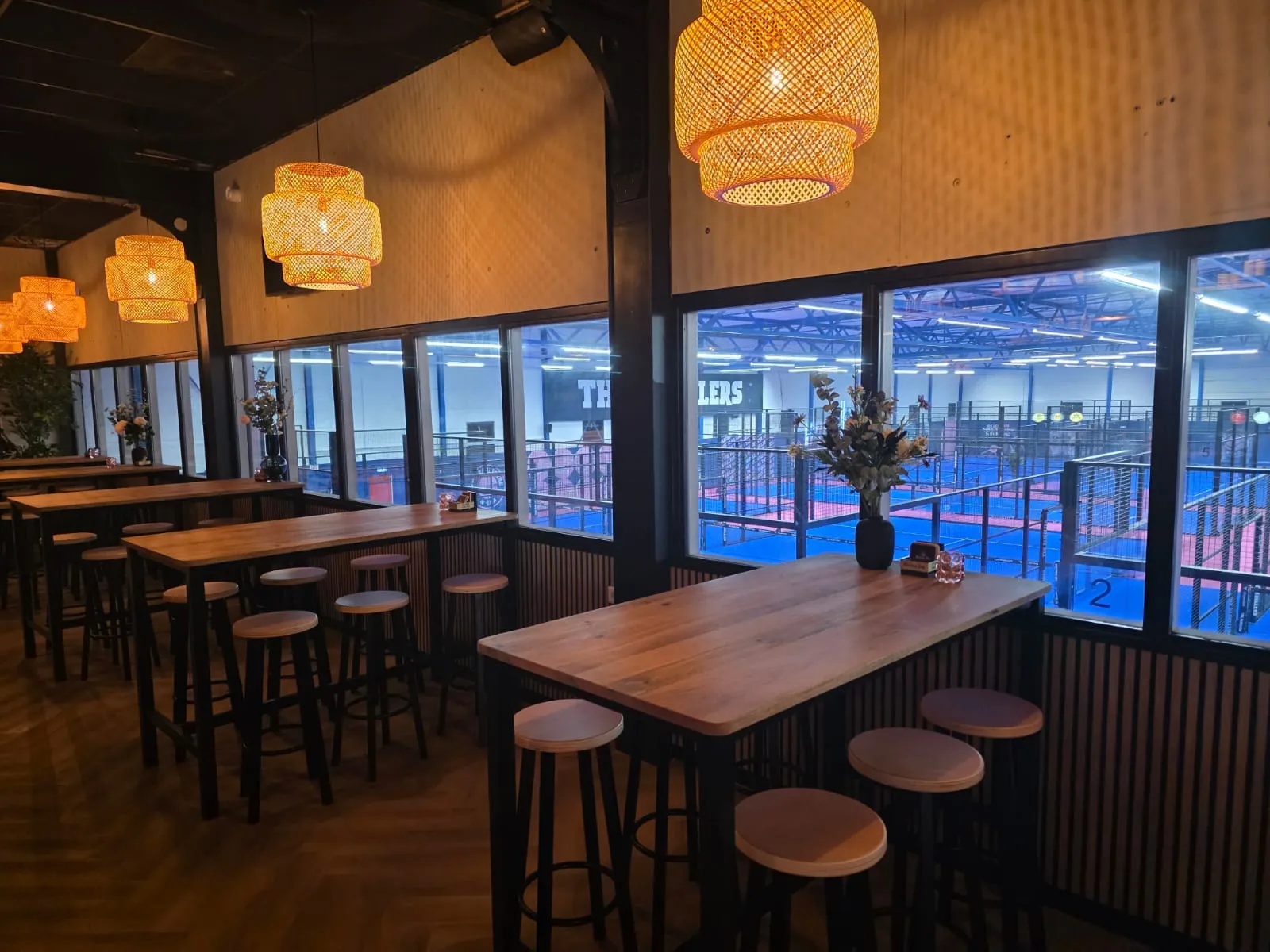 Lounge met oranje lampen met zicht op de padelbanen van The Padellers Breda