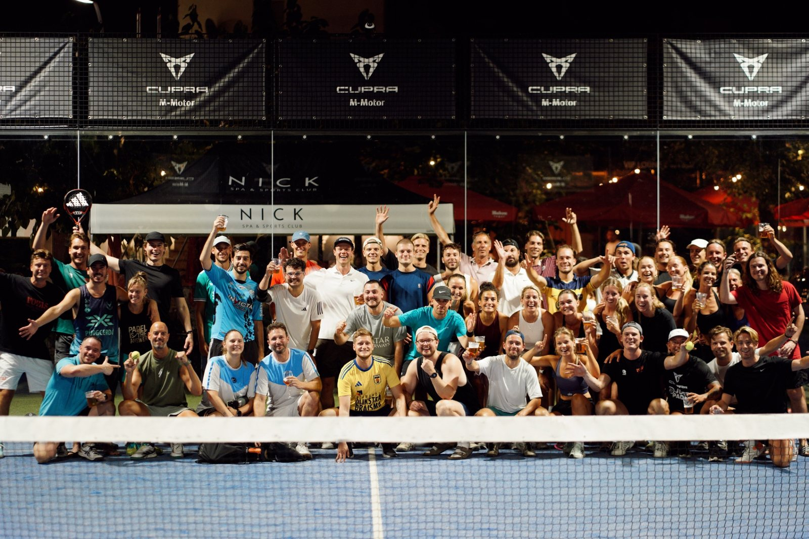Padelspelers op verlichte banen tijdens een Voyas Padel Nights event