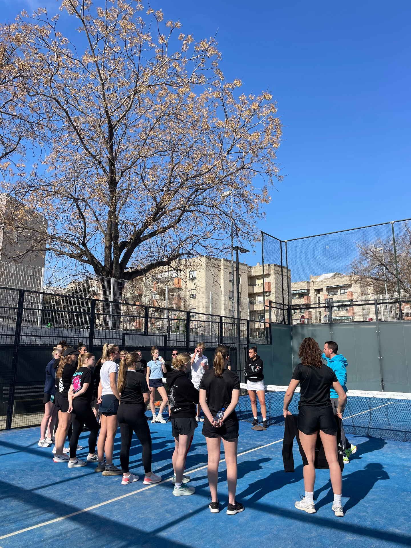 Teambespreking op de padelbaan tijdens hockeytrainingskamp
